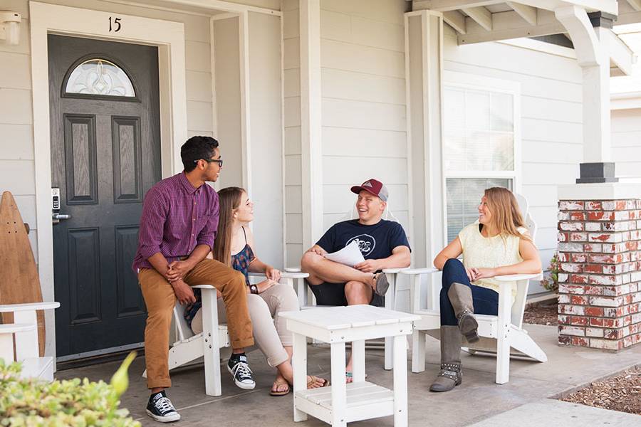 Four CBU students having a discussion on the front porch of their on-campus housing